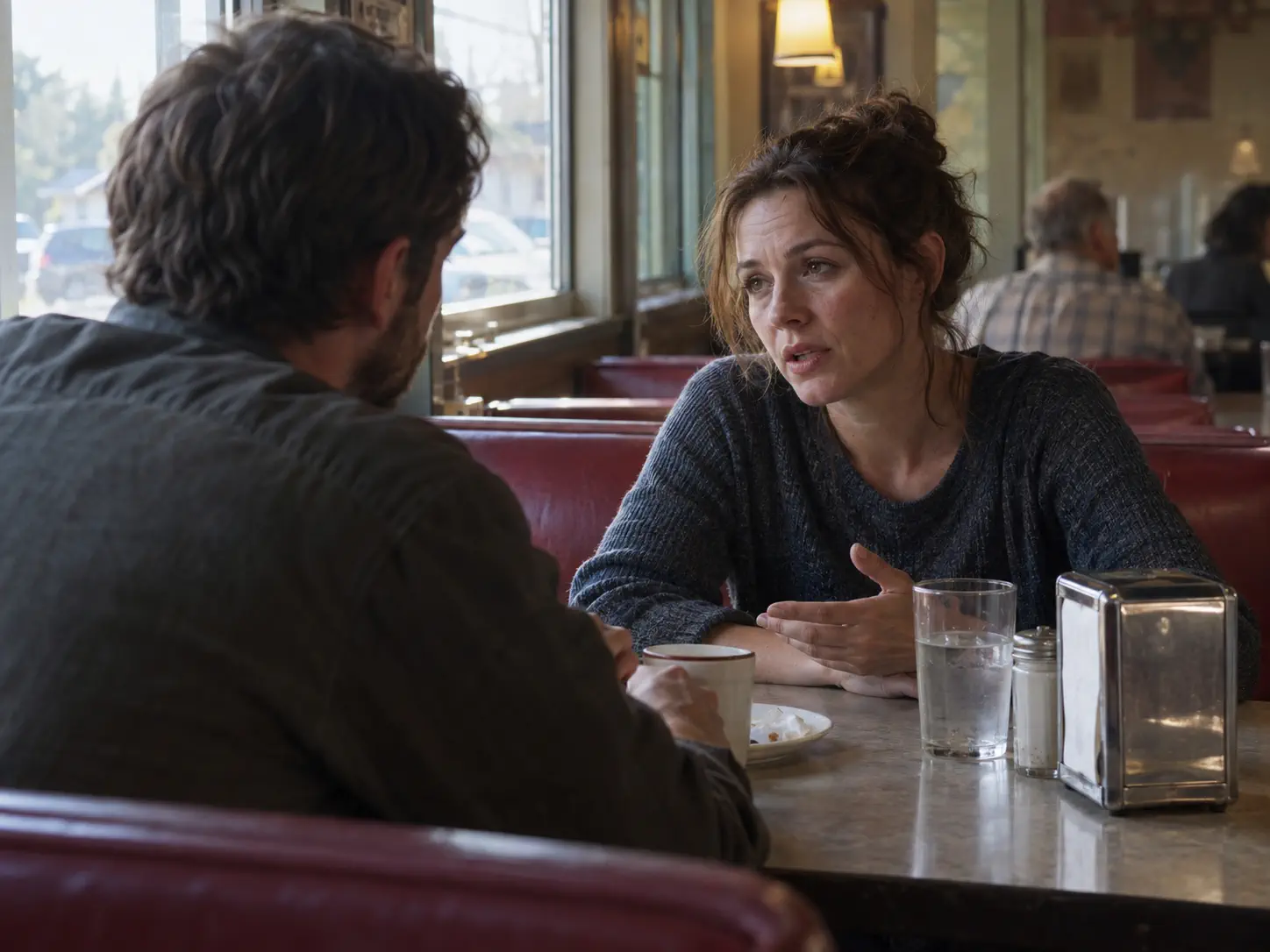 Two actors in a natural shot-reverse-shot dialogue scene inside a diner
